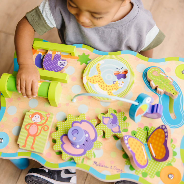 A kid playing with The Melissa & Doug First Play Children’s Jungle Wooden Activity Table for Toddlers