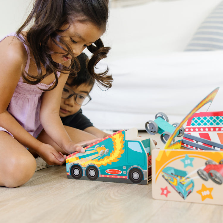 A kid playing with The Melissa & Doug Fun at the Fair! Wooden Ring of Fire Stunt Jumper Cars Game