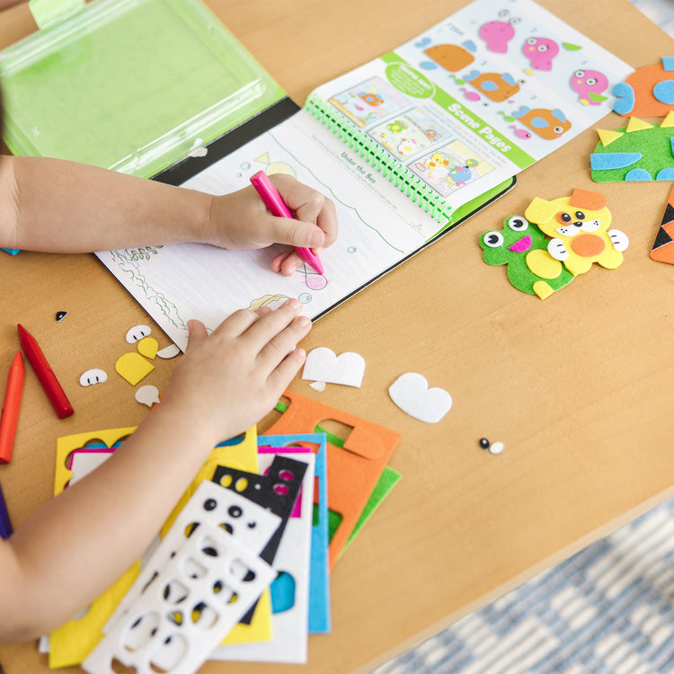 A kid playing with The Melissa & Doug On the Go Felt Friends Craft Activity Set With 188 Felt Stickers