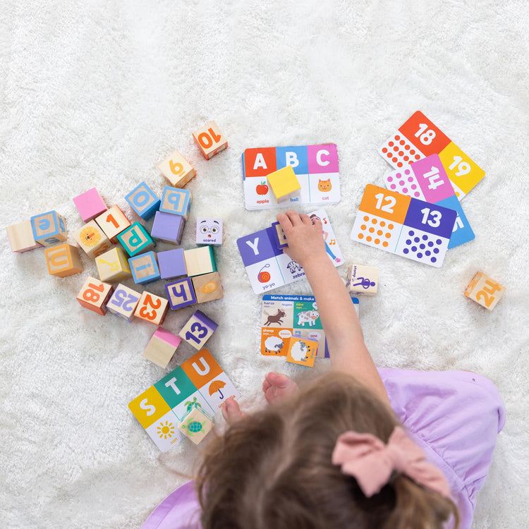 A kid playing with The Melissa & Doug Ms. Rachel Letter, Number, and Game Wooden Learning Blocks with Activity Cards for Girls and Boys Toddlers Ages 18 Months+