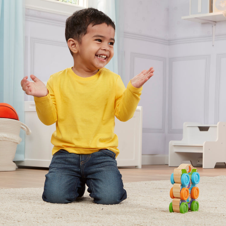 A kid playing with The Melissa & Doug First Play Wooden Animal Stacking Cars (3 pcs)