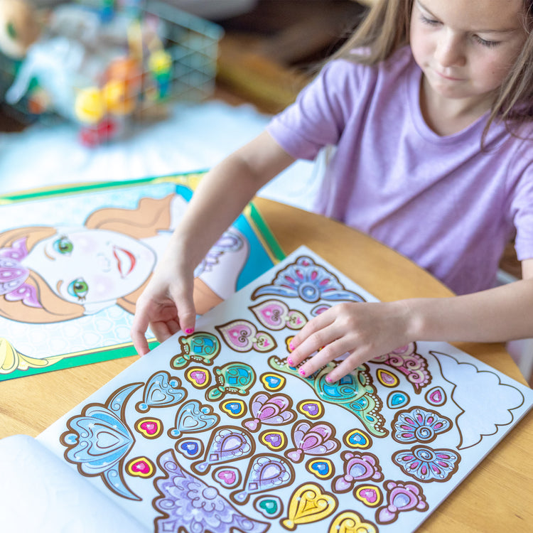 A kid playing with The Melissa & Doug Make-a-Face Sticker Pad: Sparkling Princesses - 15 Faces, 4 Sticker Sheets