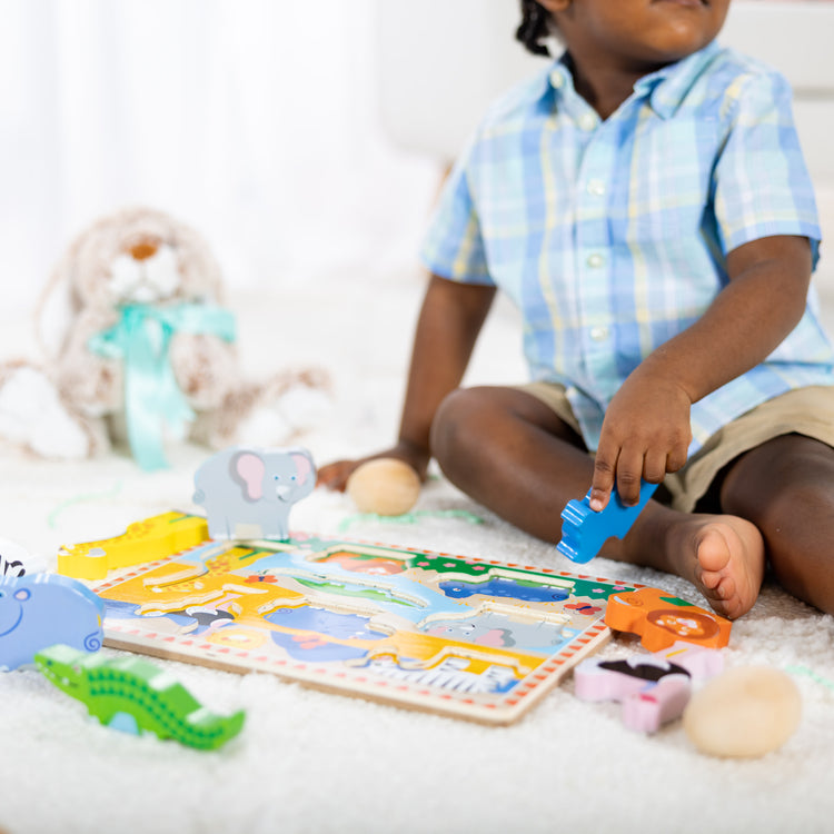 A kid playing with The Melissa & Doug Safari Wooden Chunky Puzzle - 8 Pieces