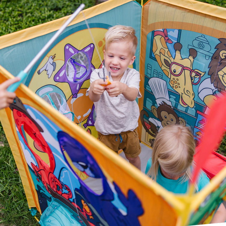 A kid playing with The Melissa & Doug Fun at the Fair! Game Center Play Tent – 4 Sides of Activities