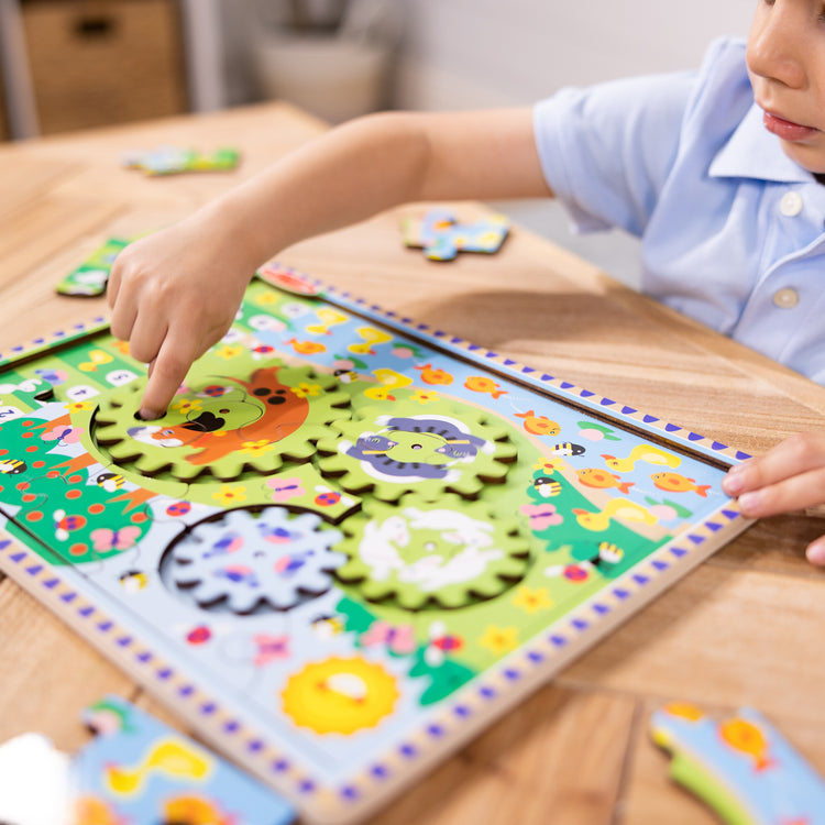 A kid playing with The Melissa & Doug Wooden Animal Chase Jigsaw Spinning Gear Puzzle – 24 Pieces