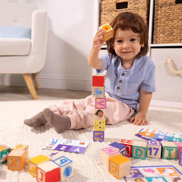 A kid playing with The Melissa & Doug Ms. Rachel Letter, Number, and Game Wooden Learning Blocks with Activity Cards for Girls and Boys Toddlers Ages 18 Months+