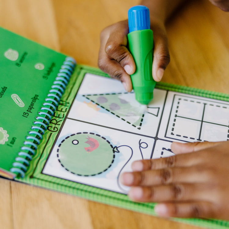 A kid playing with The Melissa & Doug On the Go Water Wow! Reusable Water-Reveal Activity Pad - Colors, Shapes