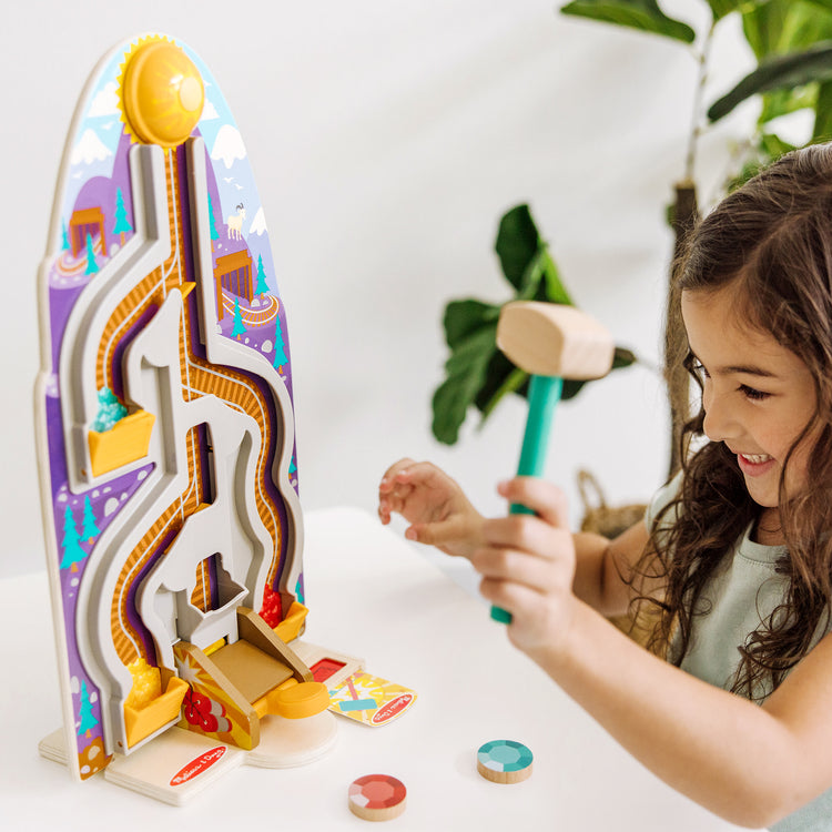 A kid playing with The Melissa & Doug Fun at the Fair! Wooden Ring the Bell Game