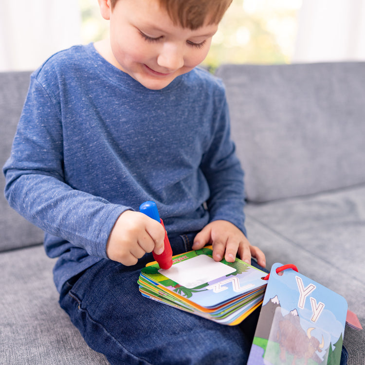 A kid playing with The Melissa & Doug On the Go Water Wow! Reusable Water-Reveal Activity Cards - Alphabet and Animals