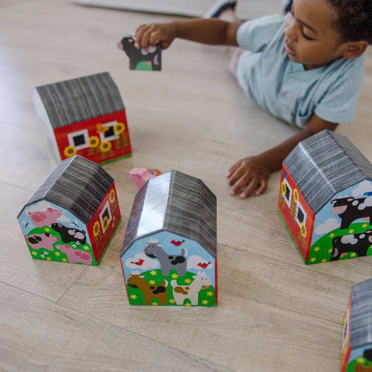 A kid playing with The Melissa & Doug Nesting and Sorting Barns and Animals With 6 Numbered Barns and Matching Wooden Animals