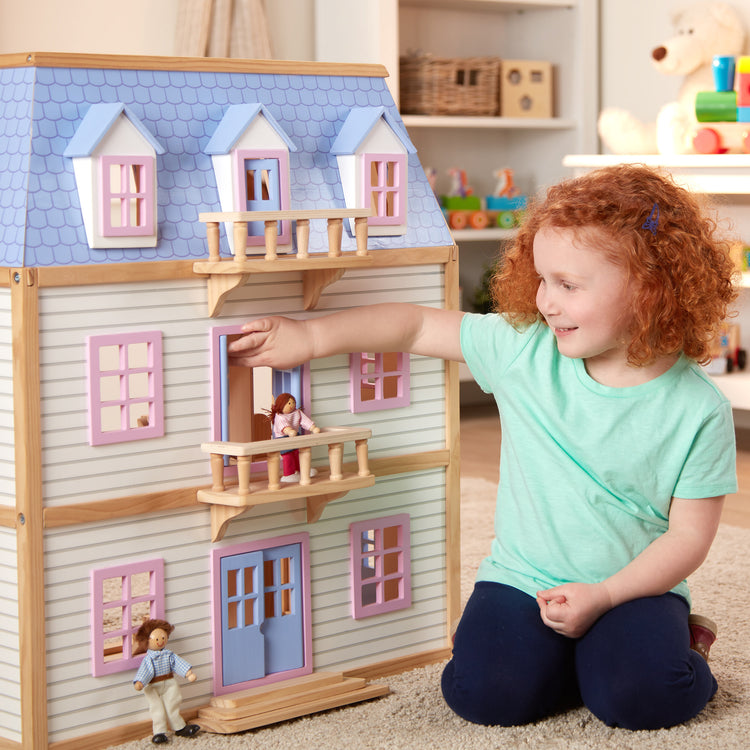 A kid playing with The Melissa & Doug Modern Wooden Multi-Level Dollhouse With 19 pcs Furniture [White]