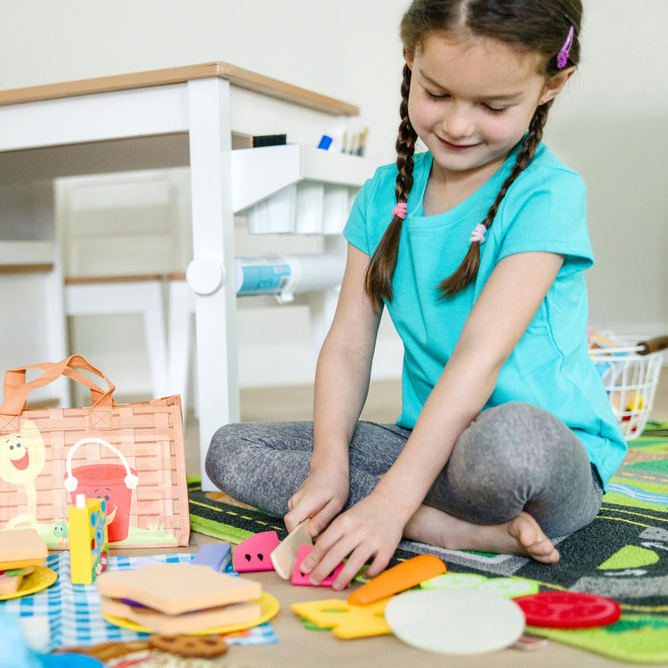 A kid playing with The Melissa & Doug Blue’s Clues & You! Share with Blue Picnic Play Set with Hand Puppet