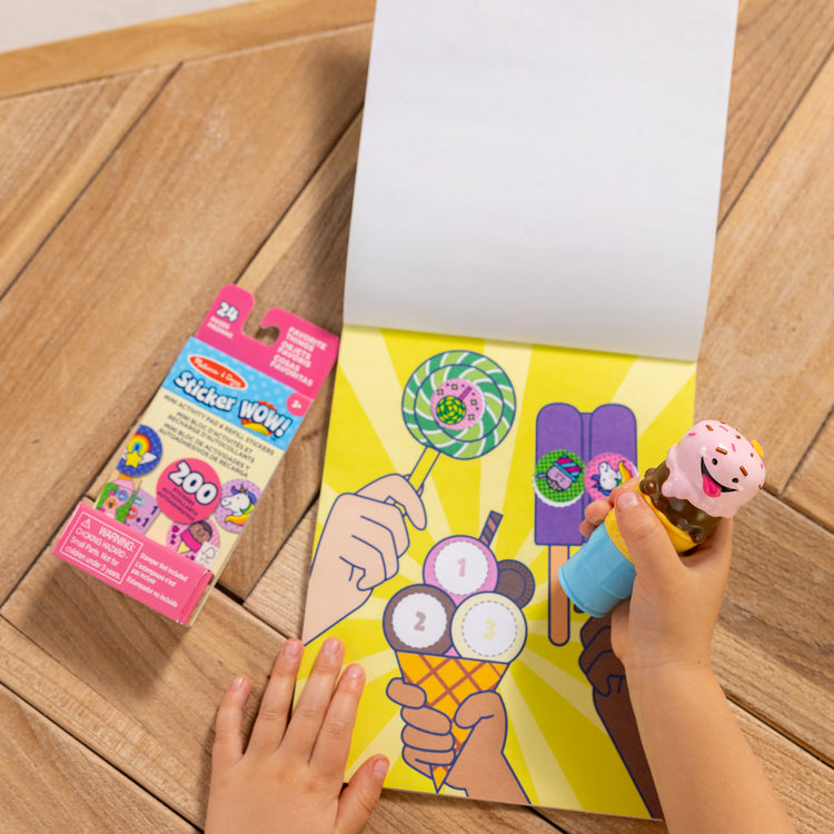 A kid playing with The Melissa & Doug Sticker WOW!™ Ice Cream Bundle: 24-Page Activity Pad, Sticker Stamper, Mini Activity Pad, 500 Stickers, Arts and Crafts Fidget Toy Collectible Character