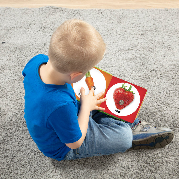 A kid playing with The Melissa & Doug Children’s Book – Poke-a-Dot: First Colors (Board Book with Buttons to Pop)