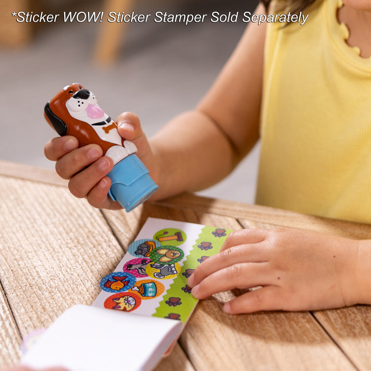 A kid playing with The Melissa & Doug Sticker WOW!™ Mini Activity Pad and 200+ Refill Stickers for Sticker Stamper Arts and Crafts Fidget Toy Collectibles – Pets Stickers