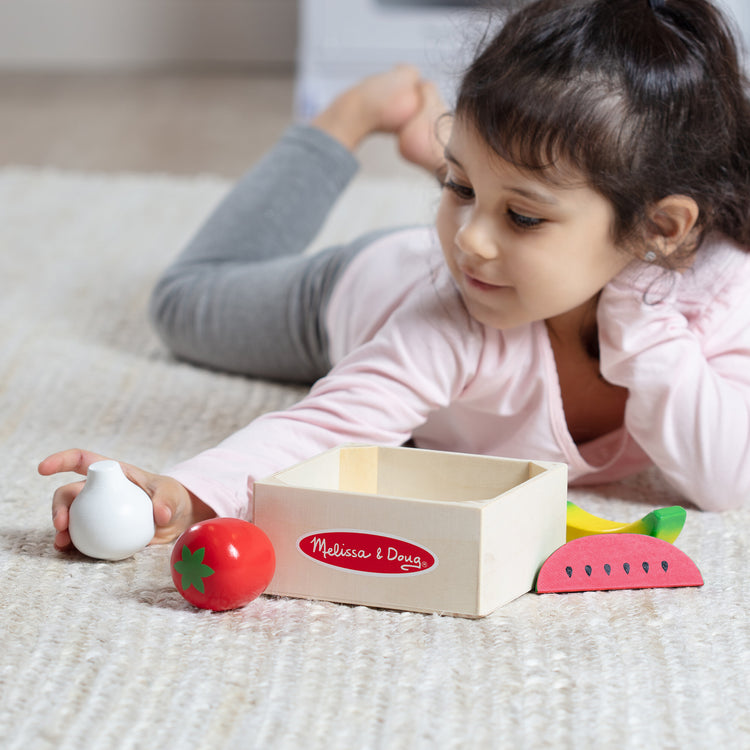 A kid playing with The Melissa & Doug Wooden Food Groups Play Food Set – Produce