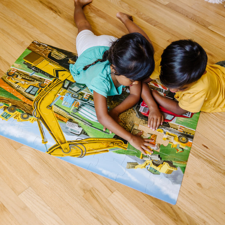 A kid playing with The Melissa & Doug Building Site Jumbo Jigsaw Floor Puzzle - 48 pcs