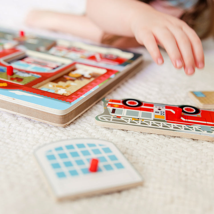 A kid playing with The Melissa & Doug Around the Fire Station Sound Puzzle - Wooden Peg Puzzle (8 pcs)