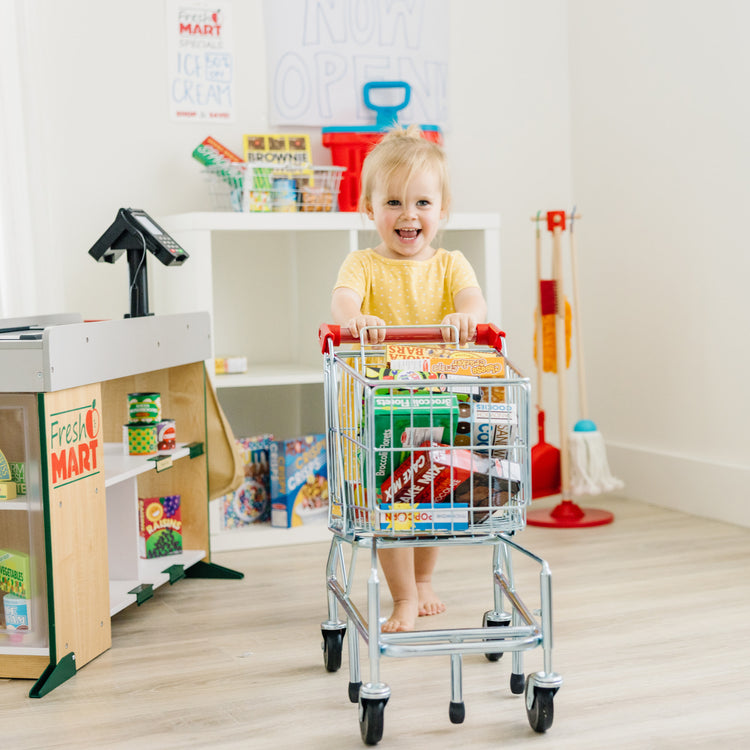 A kid playing with The Melissa & Doug Toy Shopping Cart With Sturdy Metal Frame