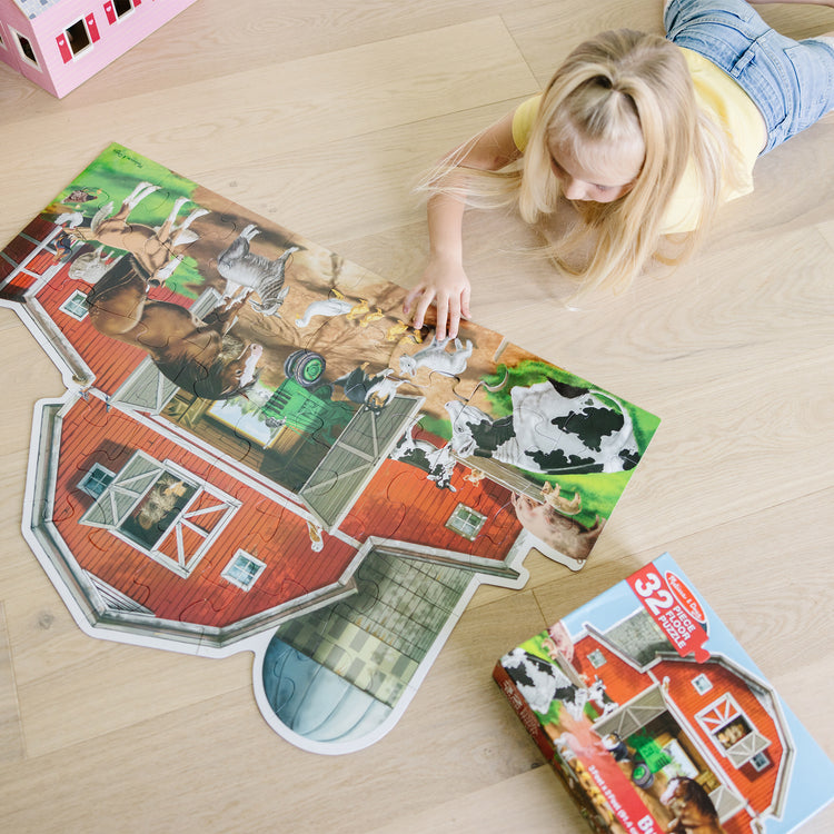 A kid playing with The Melissa & Doug Busy Barn Shaped Jumbo Jigsaw Floor Puzzle (32 pcs, 2 x 3 feet)