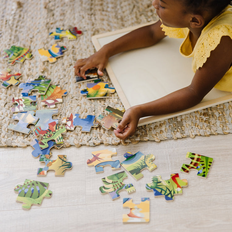 A kid playing with The Melissa & Doug Dinosaurs Wooden Jigsaw Puzzle With Storage Tray (24 pcs)