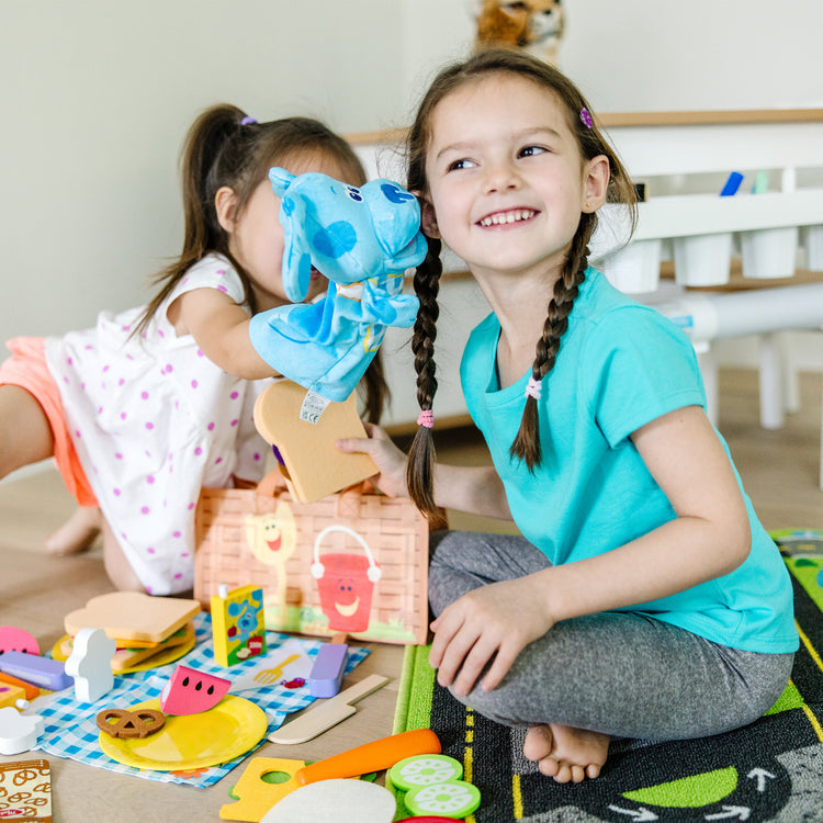 A kid playing with The Melissa & Doug Blue’s Clues & You! Share with Blue Picnic Play Set with Hand Puppet