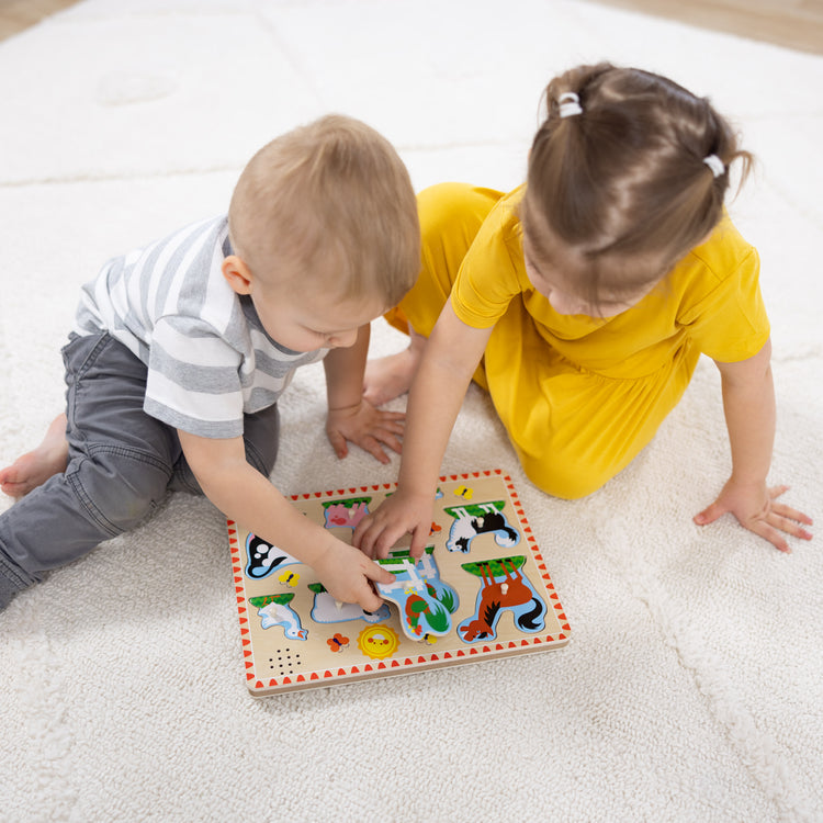 A kid playing with The Melissa & Doug Farm Animals Sound Puzzle - Wooden Peg Puzzle With Sound Effects (8 pcs)