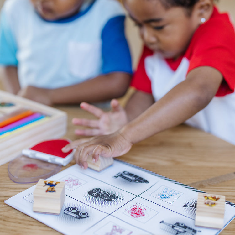 A kid playing with The Melissa & Doug PAW Patrol Wooden Stamps Activity Set With Markers, Activity Pad (25 Pieces)