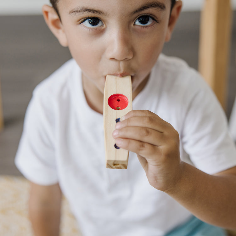 A kid playing with The Melissa & Doug Makin' Music Beginner Wooden Kazoo