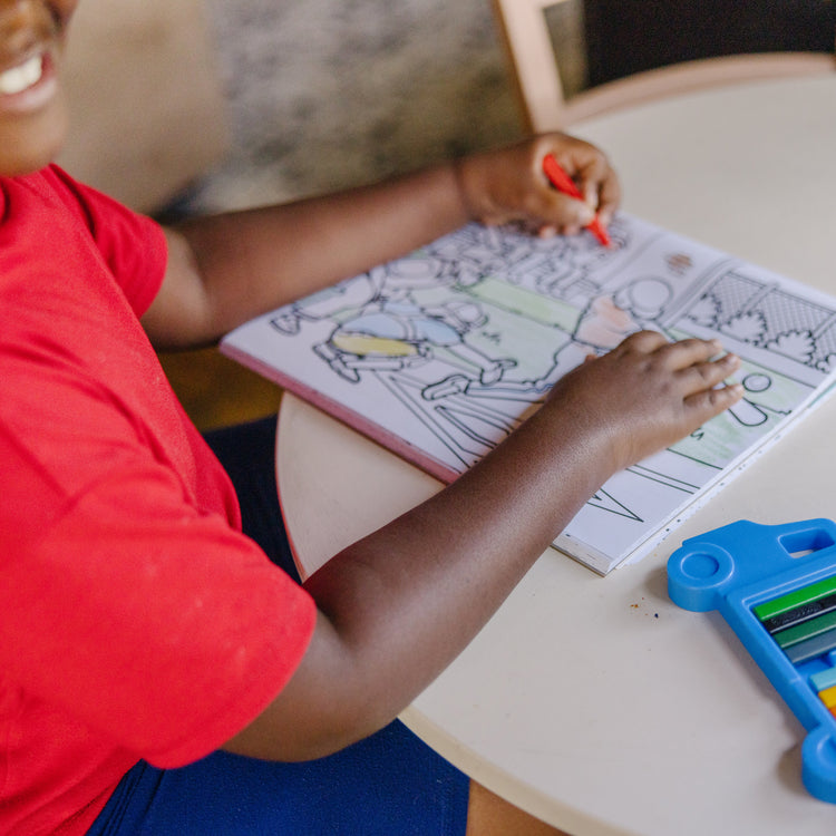 A kid playing with The Melissa & Doug Jumbo 50-Page Kids' Coloring Pad - Space, Sharks, Sports, and More