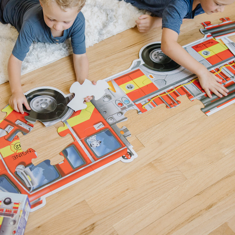 A kid playing with The Melissa & Doug Fire Truck Jumbo Jigsaw Floor Puzzle (24 pcs, 4 feet long)