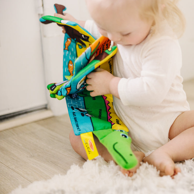 A kid playing with The Melissa & Doug Soft Activity Baby Book - Whose Feet?