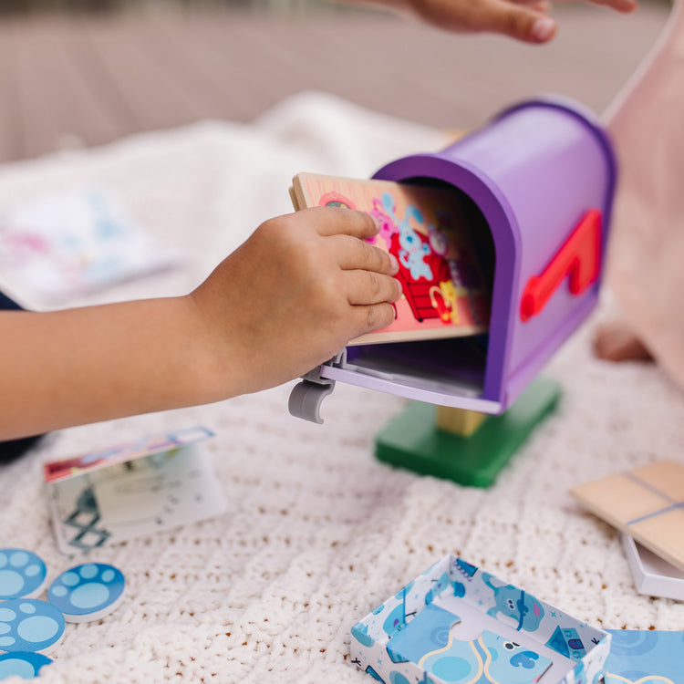 A kid playing with The Melissa & Doug Blue's Clues & You! Wooden Mailbox Play Set (27 Pieces)