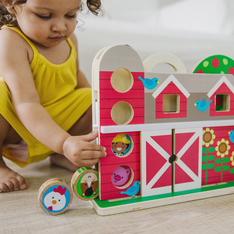 A kid playing with The Melissa & Doug GO Tots Wooden Barnyard Tumble with 4 Disks