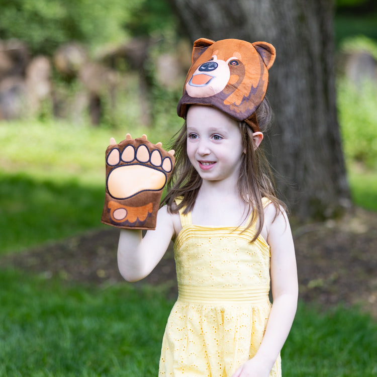 A kid playing with The Melissa & Doug Yellowstone National Park Grizzly Bear Games and Pretend Play Set with Plush Bear Heads and Bear Paw Gloves