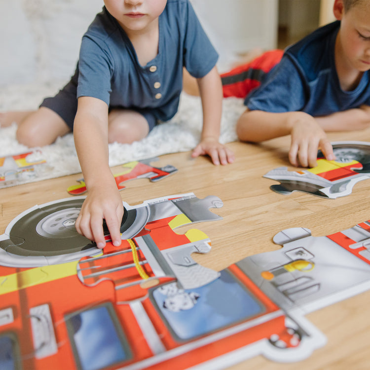 A kid playing with The Melissa & Doug Fire Truck Jumbo Jigsaw Floor Puzzle (24 pcs, 4 feet long)