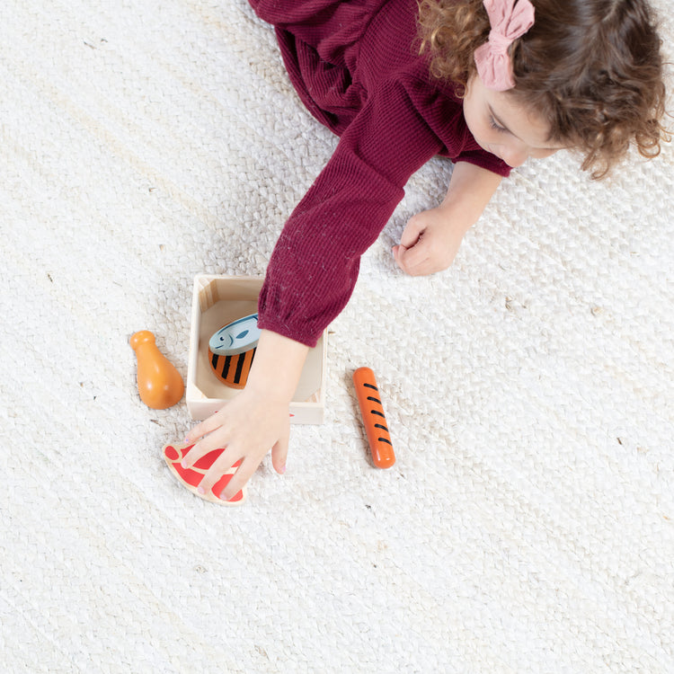 A kid playing with The Melissa & Doug Wooden Food Groups Play Food Set – Protein