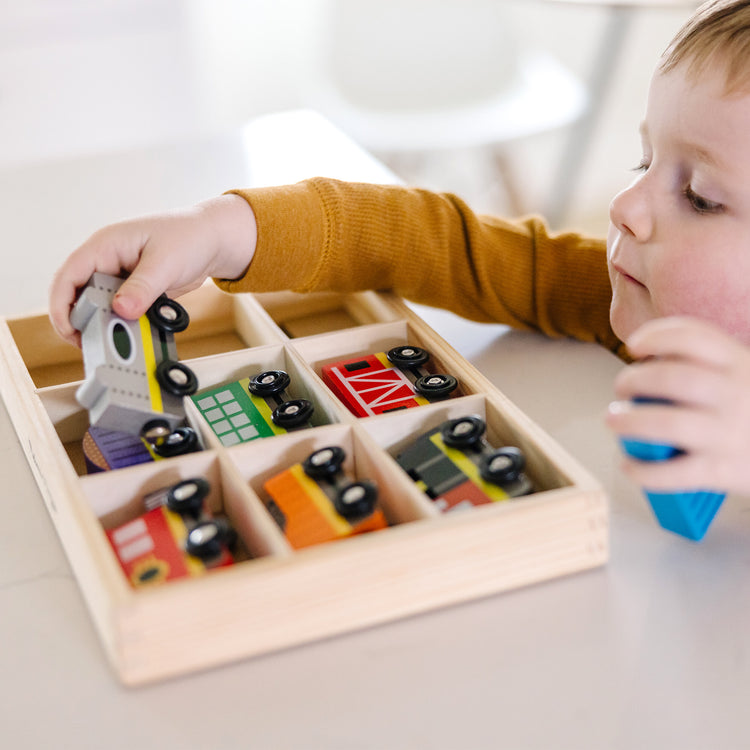 A kid playing with The Melissa & Doug Wooden Magnetic Train Cars - 8 Piece Educational and Skill-Building Wooden Toy for Boys and Girls