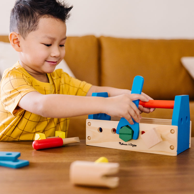 A kid playing with The Melissa & Doug Take-Along Tool Kit Wooden Construction Toy (24 pcs)