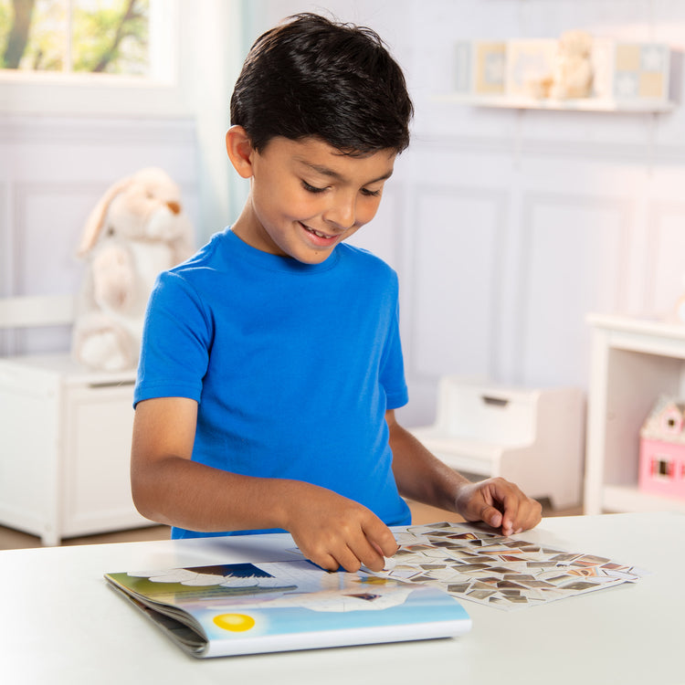 A kid playing with The Melissa & Doug Mosaic Sticker Pad Safari Animals (12 Color Scenes to Complete with 850+ Stickers)