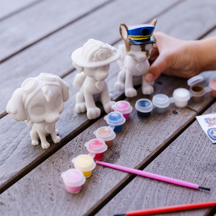 A kid playing with The Melissa & Doug PAW Patrol Craft Kit - 3 Decorate Your Own Pup Figurines