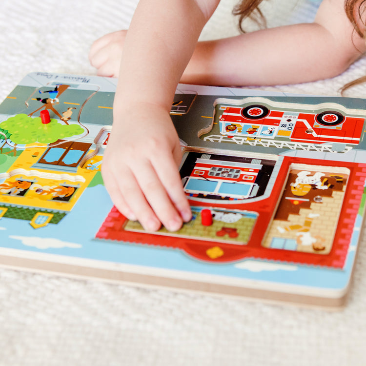 A kid playing with The Melissa & Doug Around the Fire Station Sound Puzzle - Wooden Peg Puzzle (8 pcs)