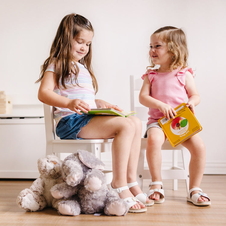 A kid playing with The Melissa & Doug Wooden Chairs, Set of 2 - White Furniture for Playroom