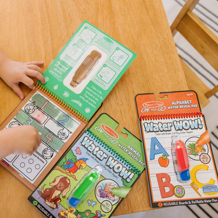 A kid playing with The Melissa & Doug Water Wow! - Water Reveal Pad Bundle - Animals, Alphabet, Numbers and More