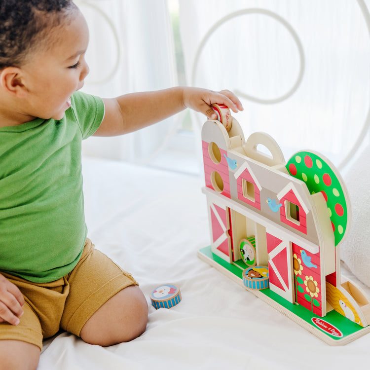 A kid playing with The Melissa & Doug GO Tots Wooden Barnyard Tumble with 4 Disks