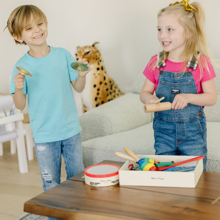 A kid playing with The Melissa & Doug Band-in-a-Box Clap! Clang! Tap! - 10-Piece Musical Instrument Set