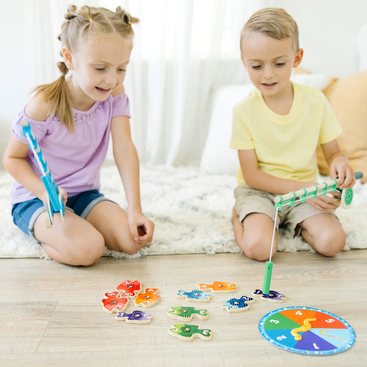 A kid playing with The Melissa & Doug Catch & Count Wooden Fishing Game With 2 Magnetic Rods