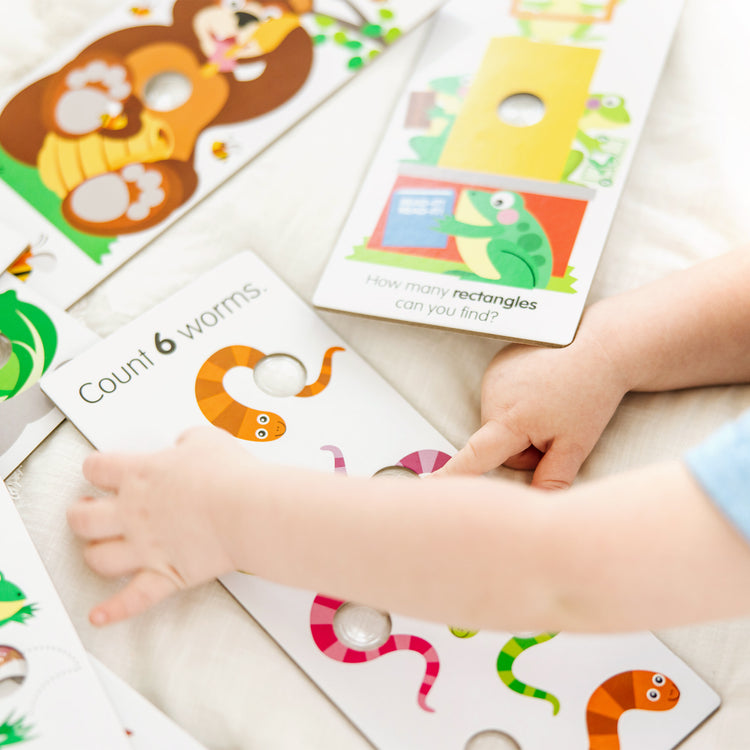 A kid playing with The Melissa & Doug Poke-A-Dot Jumbo Number Learning Cards - 13 Double-Sided Numbers, Shapes, and Colors Cards with Buttons to Pop