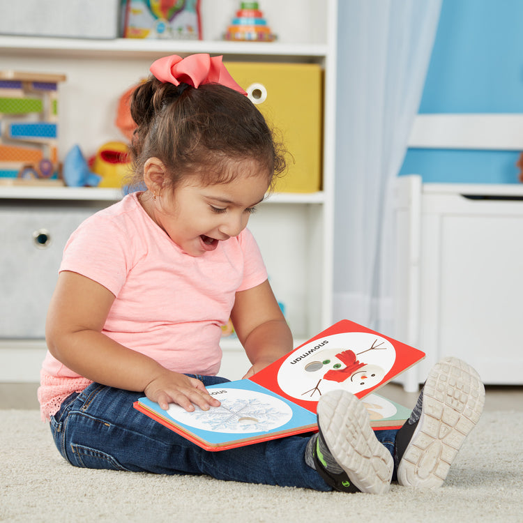 A kid playing with The Melissa & Doug Children’s Book – Poke-a-Dot: Christmas (Board Book with Buttons to Pop)