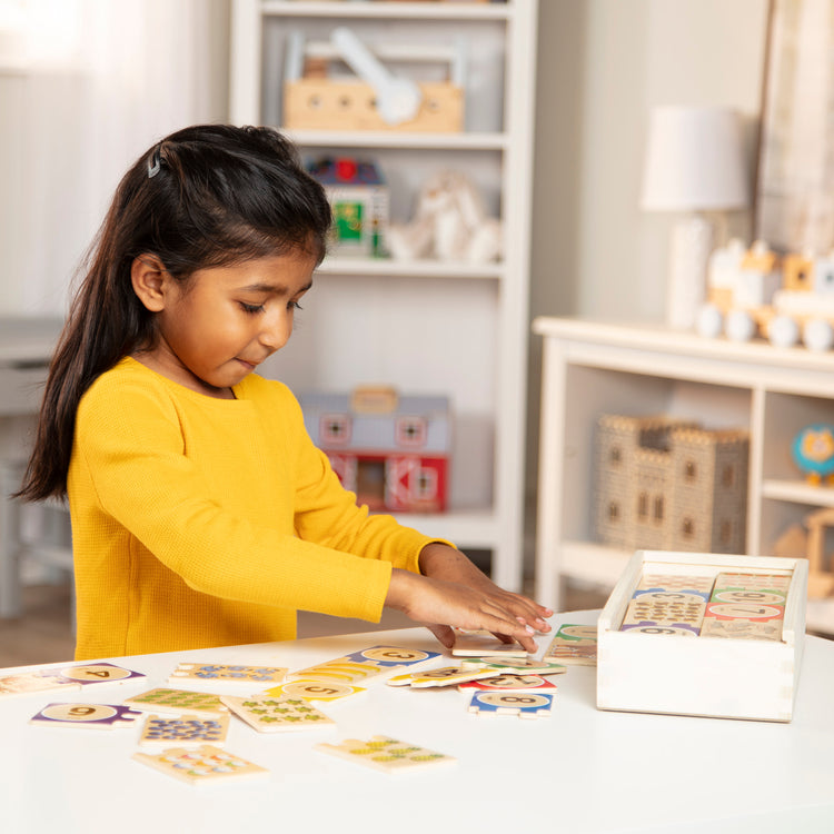 A kid playing with The Melissa & Doug Self-Correcting Wooden Number Puzzles With Storage Box (40 pcs)